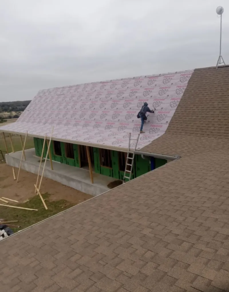 Worker preparing underlayment for a metal roof installation in Rushville